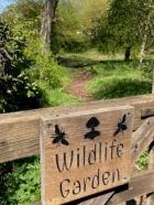 A wooden gate with a wooden sign reads "wildlife garden"