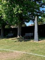 Slate monument set in the tree line with shade in the background.