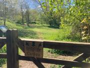 A wooden gate with a wooden sign reads "wildlife garden", grass and trees 